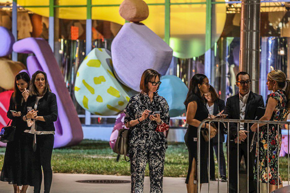 Unas personas esperan la llegada de sus autos frente a la entrada del Centro de Convenciones de Miami Beach, sede de la Feria de Art Basel, este miércoles en Miami Beach, Florida. Yates y automóviles de lujo, el desfile de famosos, vividores y colecc