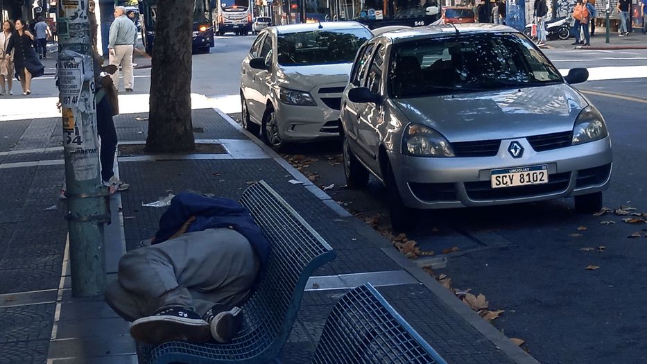 Una persona duerme sobre un banco de la principal avenida de Montevideo. Foto: Alejandro Andrada
