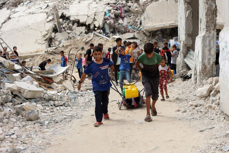 Niños palestinos desplazados cargan agua para distribuir en barrios de Ciudad de Gaza, el día del aniversario del ataque inicial de Hamás en Israel. Foto: Omar AL-QATTAA / AFP.