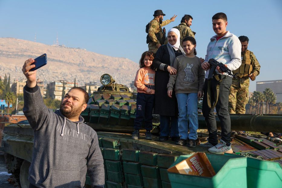 Una familia siria celebra la caída de Al Asad posando para una foto sobre un tanque de guerra. Foto: Omar Haj Kadoura / AFP