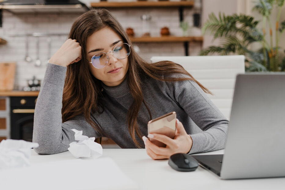 Joven procrastina mirando el celular. Foto: Freepik
